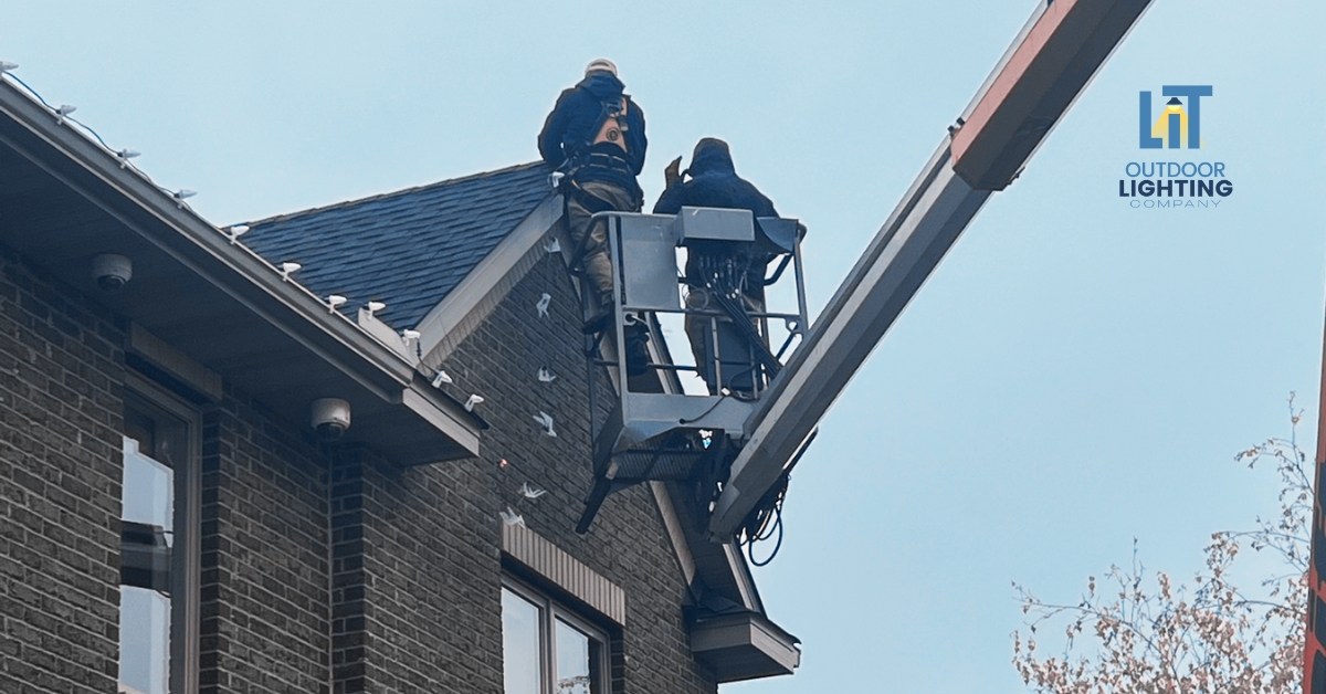 Electrician holding holiday lights near a home
